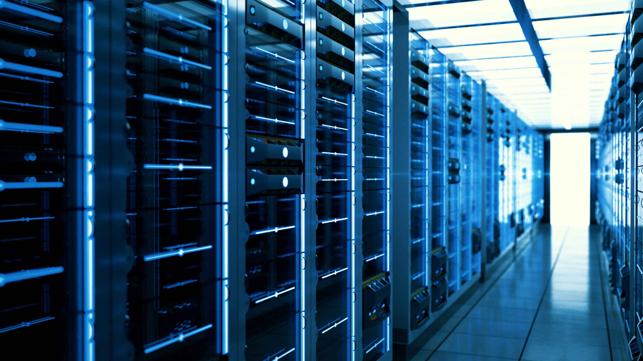 Long rows of large server racks stretch through a data center interior, illuminated by a cool, dominant blue light emanating from the equipment and aisles.